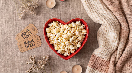 Sweet heart-shaped popcorn bowl and movie tickets create a cozy Valentine's Day flatlay at home