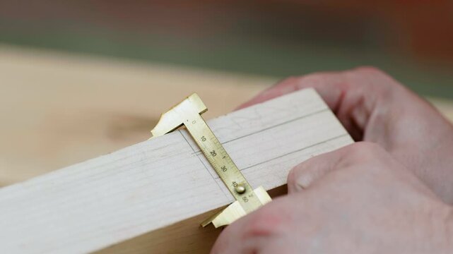 A person is using a caliper to measure wood in a well-lit workshop. The focus is on ensuring accurate dimensions for a wood crafting task.