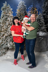 Grandparents posing with grandchild during festive Christmas. baby is dressed in Santa hat and holiday sweater, held lovingly by smiling grandparents. Snow-covered Christmas trees and warm twinkling 