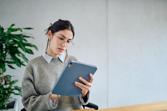 Young professional woman using a digital tablet for work, focusing on business tasks in a contemporary office environment