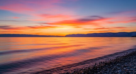 Vibrant sunset over tranquil lake with colorful sky and gentle waves.