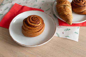 Cinnamon roll and freshly baked pastries on cozy table setting. Christmas mood