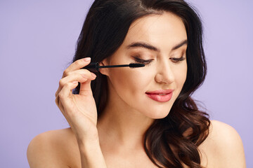 Fototapeta premium Beautiful woman applying mascara with elegance and style in a bright setting