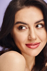 Obraz premium Young beautiful woman smiling warmly in a soft purple backdrop with graceful elegance