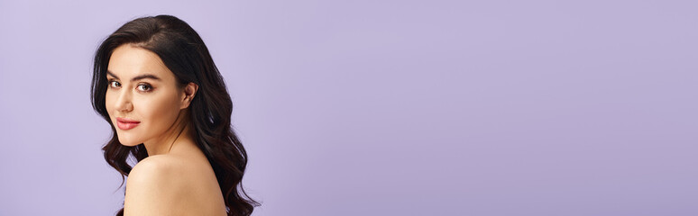 Naklejka premium Beautiful young woman with flowing hair poses gracefully against a soft lavender backdrop