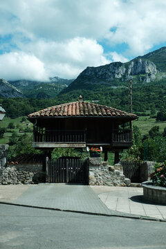 Traditional granary of the rural areas of Northern Spain. Iconic wooden structure horreo with mountains and blue sky with white clouds at the background. Film-like colors