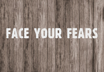 The inscription &laquo;Face your fears&raquo; on old wooden boards