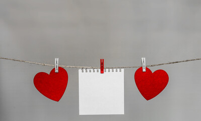 Photo of two hearts and a blank sheet of paper on an abstract background