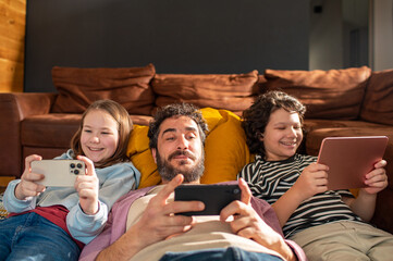 Adult father with young son and daughter gaming in living room, happy