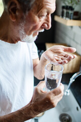 Senior man calmly taking medication in home kitchen