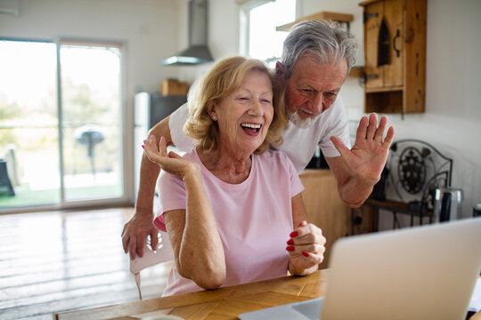 Senior couple laughing while video calling in home kitchen