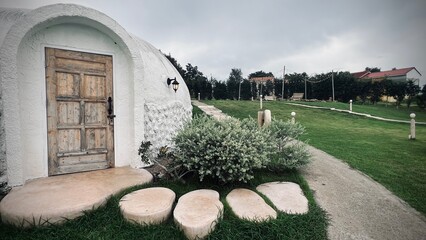Ratchaburi, Thailand :Beautiful architecture of white dome bungalow with arch window and door linked by a walkway on lush green lawn with mountain view at IGLOO Suanphueng resort. © Veruree