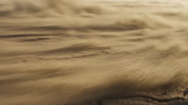 Cracked Dry Earth with Blowing Sand in Arid Desert Landscape, Symbolizing Drought