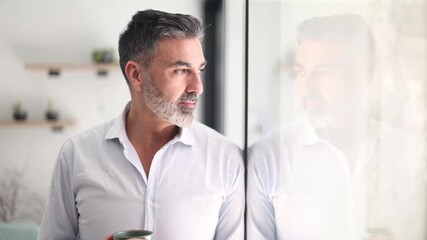 Mature businessman contemplating while drinking coffee by the window - Powered by Adobe