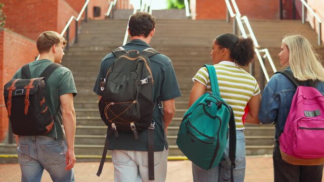 Group of diverse students with backpacks walking up stairs