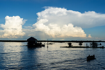 Floating village on Tonle Sap Lake with boats and dramatic cloudscape