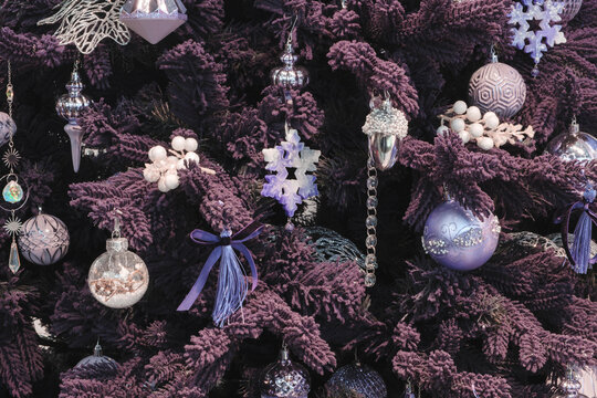 A purple Christmas tree with lots of ornaments. The ornaments are purple, including snowflakes.