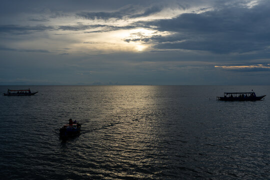 Boats on the water at sunset with a dramatic sky and sun reflections