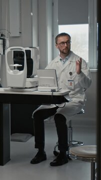 Vertical full length shot of mature man as doctor performing eye exam using modern diagnostic machine in optometry room