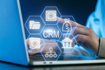 Business professional using CRM software on laptop while analyzing data at night