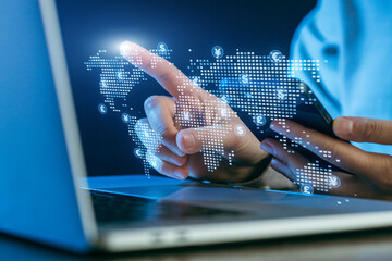 Digital connection and finance: a person interacting with a smartphone and laptop in a modern workspace