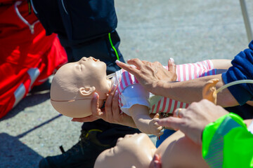Hands demonstrating infant first aid on CPR mannequin