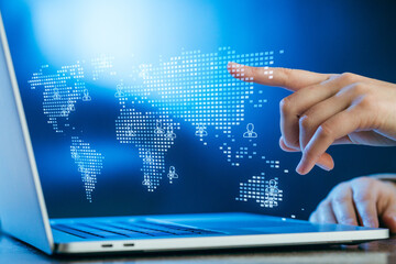 Hand interacting with a digital world map on a laptop, symbolizing global connectivity and technology in modern communication