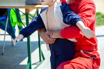 Person demonstrating choking first aid on child mannequin