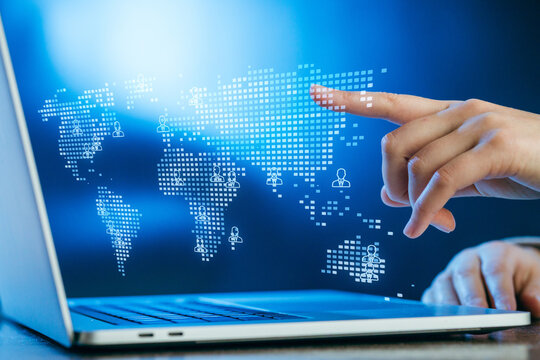 Hand interacting with a digital world map on a laptop, symbolizing global connectivity and technology in modern communication
