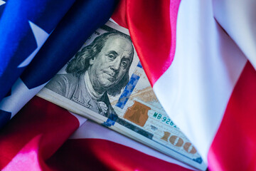 American flag draped over a hundred-dollar bill reveals national pride and economic strength