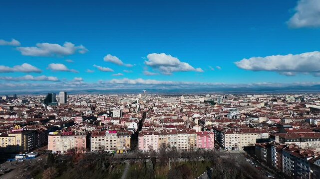 Short drone video of Sofia captured from the NDK area, filmed with a panoramic sweep on a sunny January 1, 2019. The background reveals the city center and the full urban landscape.