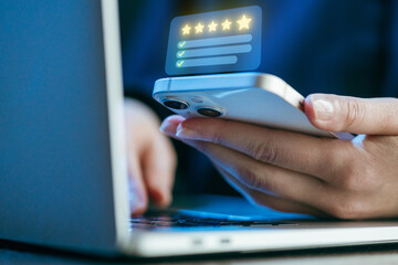 User reviews smartphone feedback while working on a laptop in a modern office setting