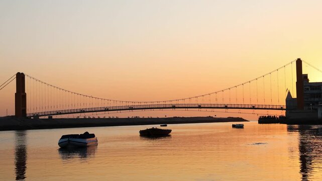 picturesque sunset landscape featuring suspension bridge and waterfront silhouettes
