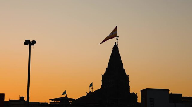 silhouette of ancient hindu dwarkadhish temple shikhara with holy flag at sunset sky