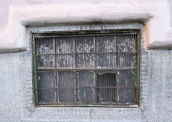 Old, rusted window with a broken pane reflects the passage of time in an urban setting