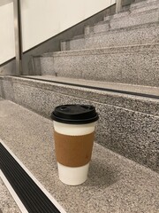 Disposable coffee cup on indoor staircase in modern building