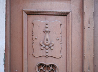 Decorative wooden door with heart-shaped mail slot and ornate carvings in a historic urban setting