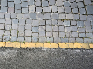 Detailed view of a cobblestone pavement with yellow line along the edge in a urban setting
