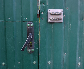 Green metal door with lock and security system near urban area at dusk