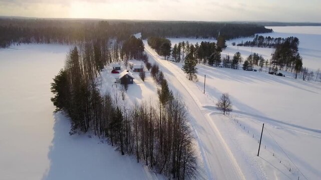 Aerial view of Scenic Winter Landscape Featuring a Remote Cabin Surrounded by Snow-Covered Fields and Tall Trees in a Serene, Sunlit Atmosphere in Finland