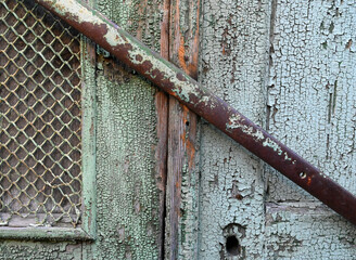Old wooden door with peeling paint and rusty iron bar in an abandoned building