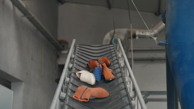 mixed footwear transported on conveyor belt inside recycling facility