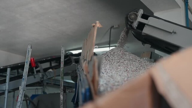 slowmotion stream of recycled rubber granules falling from conveyor