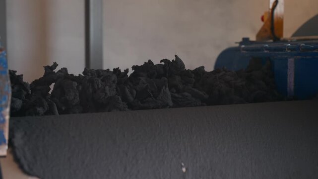 dark rubber scraps moving along industrial rollers