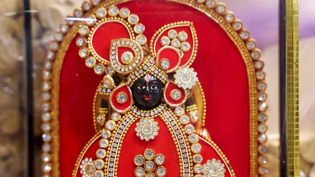 ornate deity dwarkadhish idol adorned with red velvet and sparkling stone embellishments