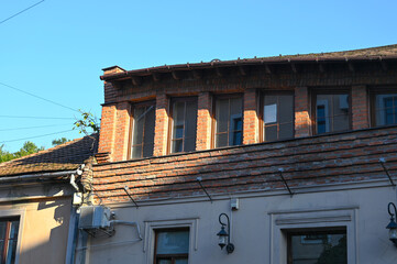 Brick building with windows and roof details under clear blue sky in a quiet urban area