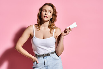 Young woman shares her skin care routine in a dreamy pink studio setting