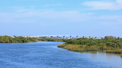 Scenic view of a bridge over a river with lush green vegetation under a blue sky