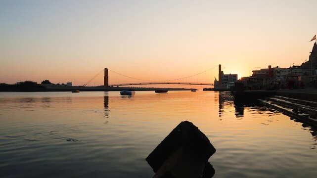 dramatic orange sky over river with bridge silhouette and calm water