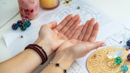 Hands holding a set of rune stones, with astrological charts in the background. Fortune telling